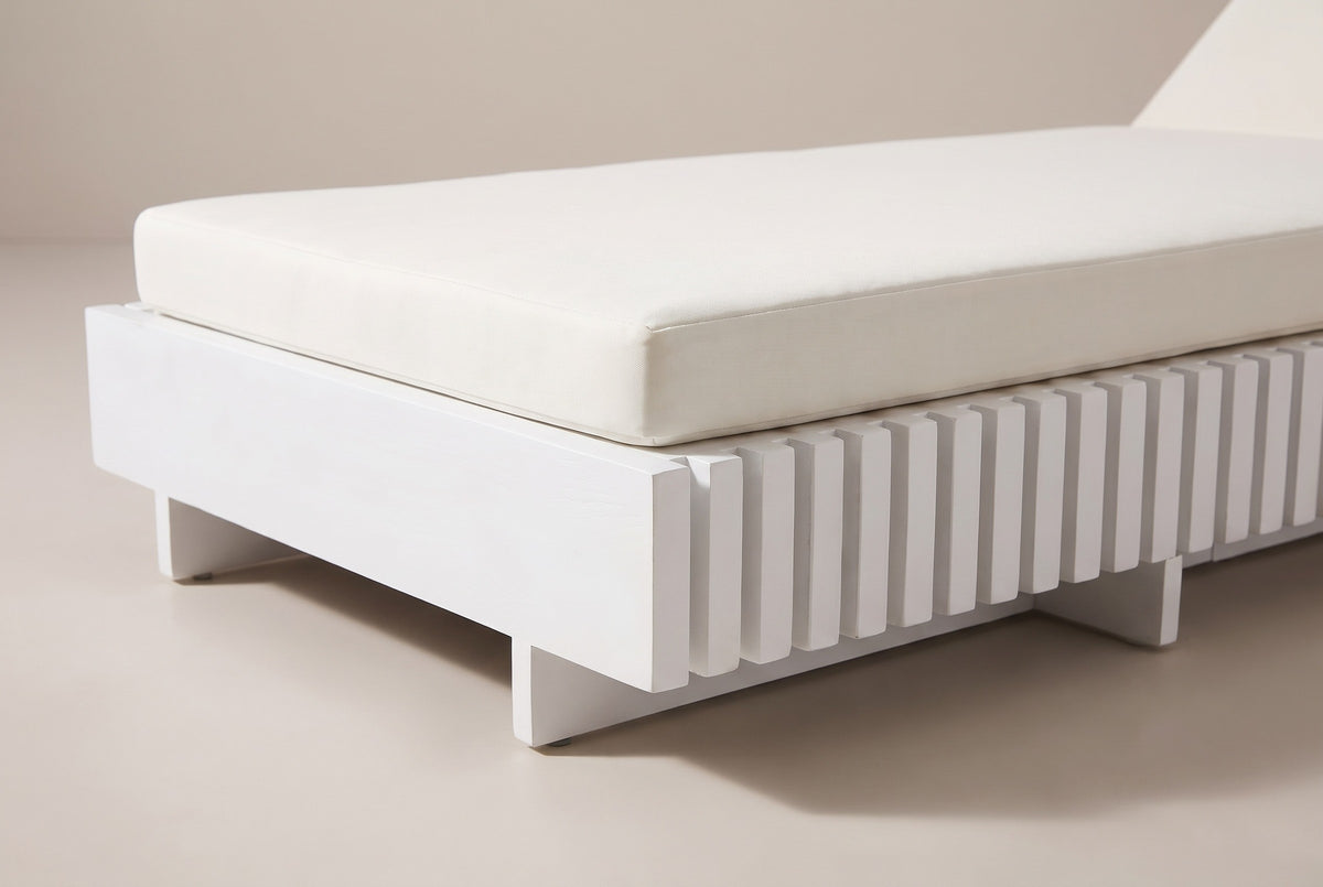 Close-up of the Riesi chaise: the white-painted acacia foot end board and vertical battens, with the ivory cushion above