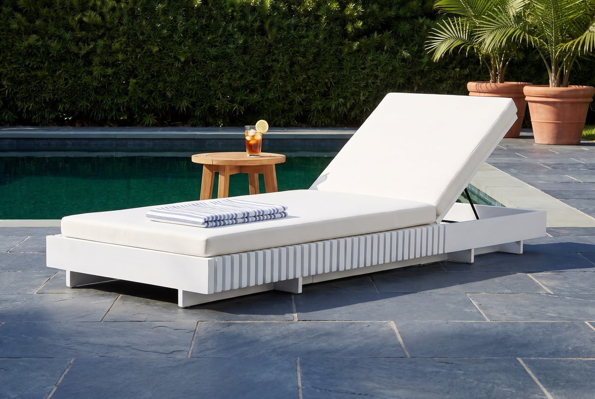 Riesi white acacia chaise lounge on a dark slate pool terrace in Naples, Florida, a clipped hedge and potted palms behind (side table not included)