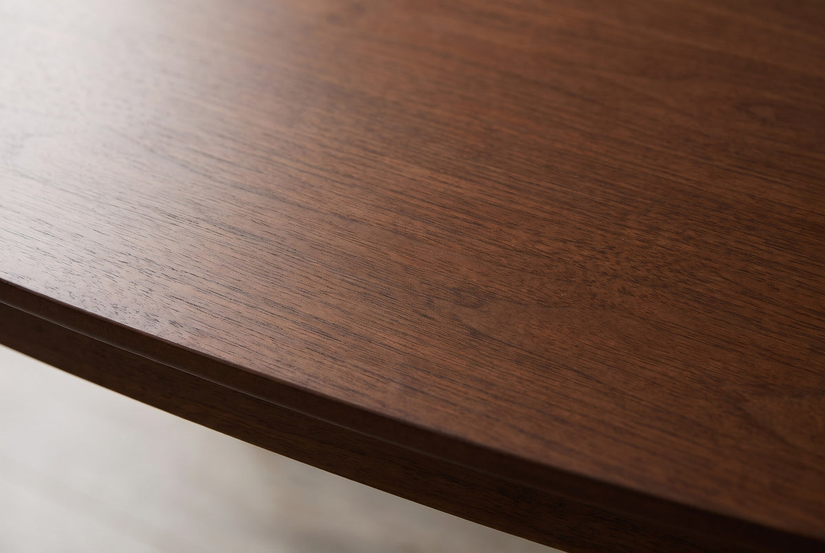 Close-up of the walnut veneer on the Rossano table: fine grain in a dark reddish brown running to the thin bevelled edge of the top