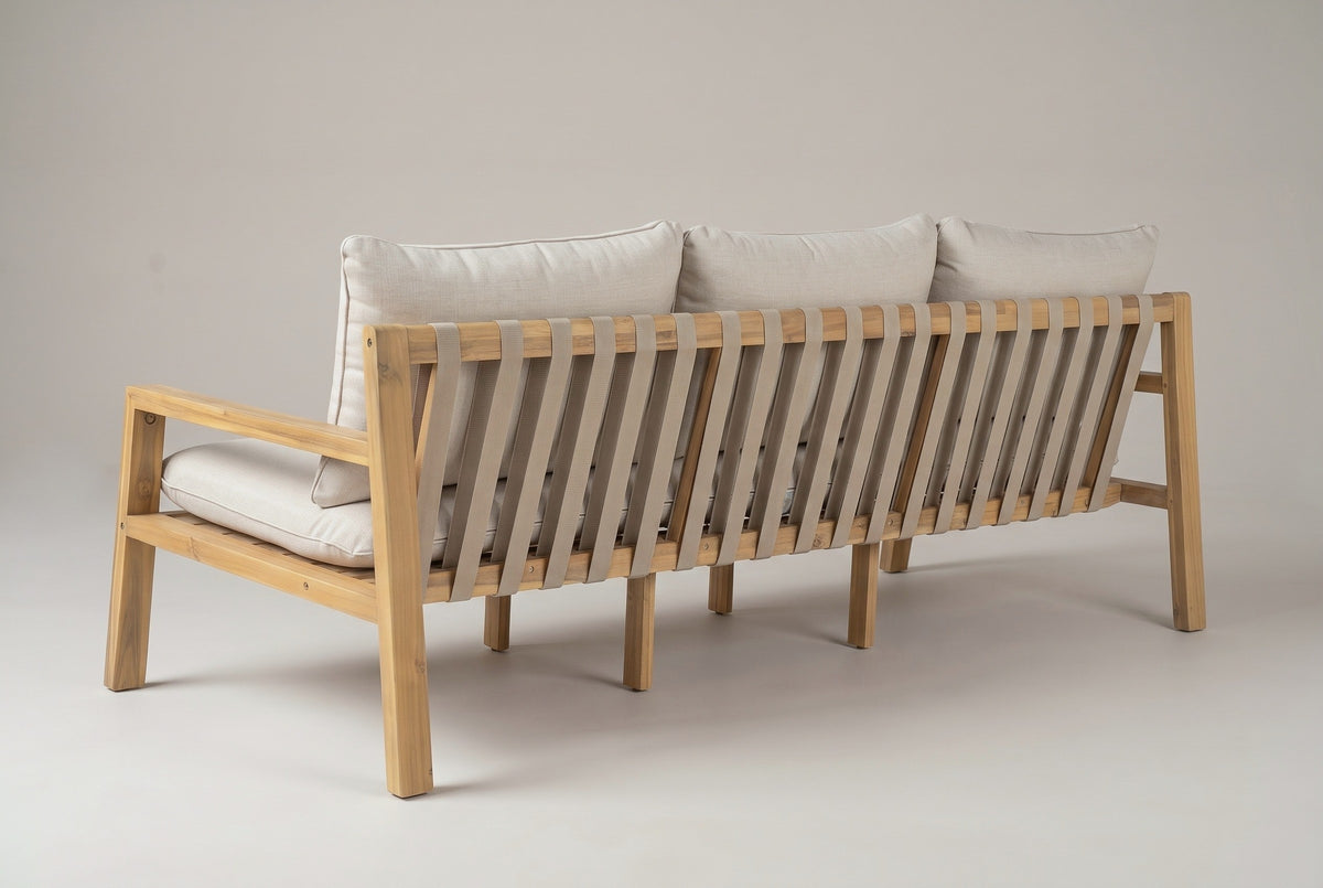 The Sambuca sofa from behind: vertical taupe straps on the leaning acacia back frame, the back cushions above, a slim arm and the square legs
