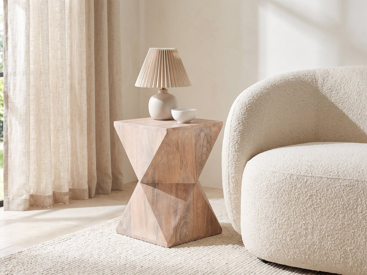 Santeramo Cerused Mango Faceted Side Table with a lamp and a ceramic bowl beside a cream boucle armchair in a bright plaster room
