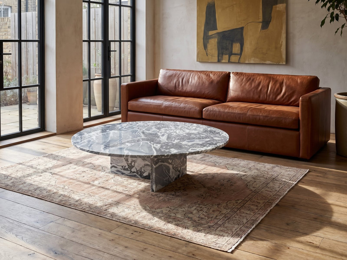 Saturnia Blue-Grey Marble Coffee Table on a vintage rug in front of a leather sofa in an industrial loft