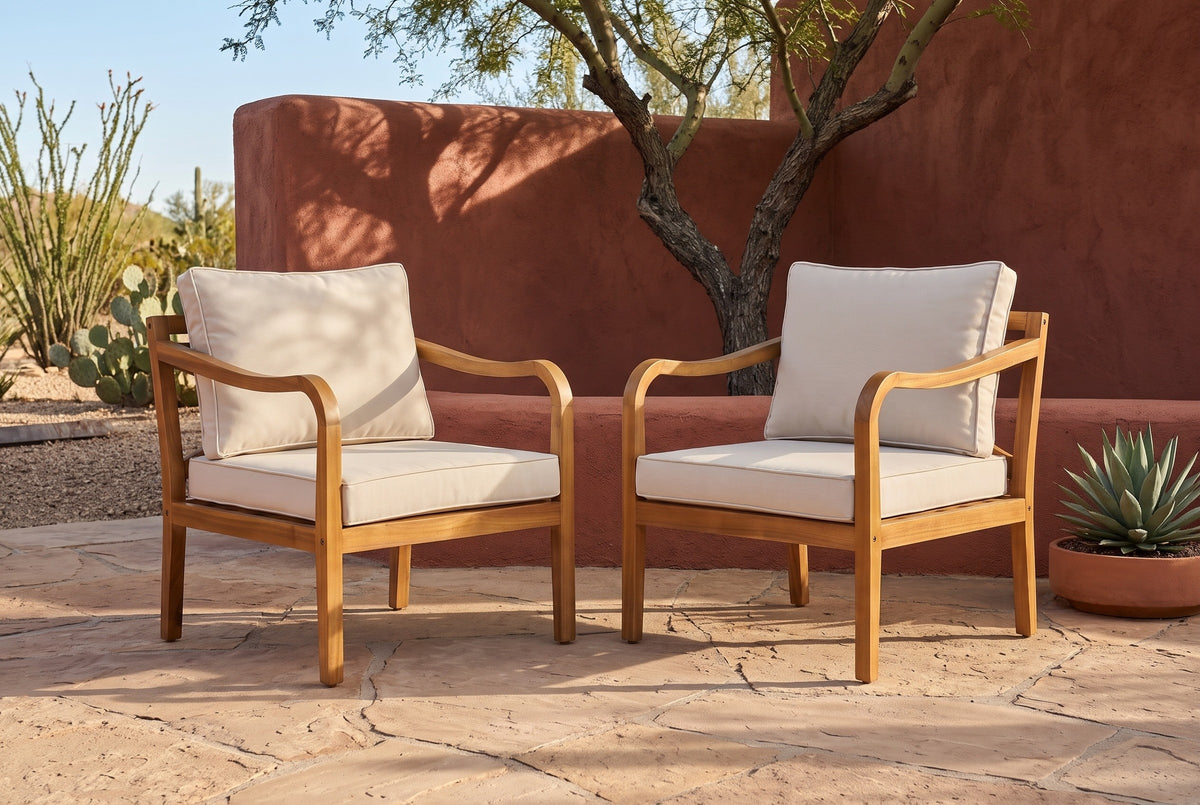 Two Savoca acacia club chairs on sandstone flagstones in front of a terracotta adobe wall in a Tucson desert patio, a mesquite tree behind (planter not included)
