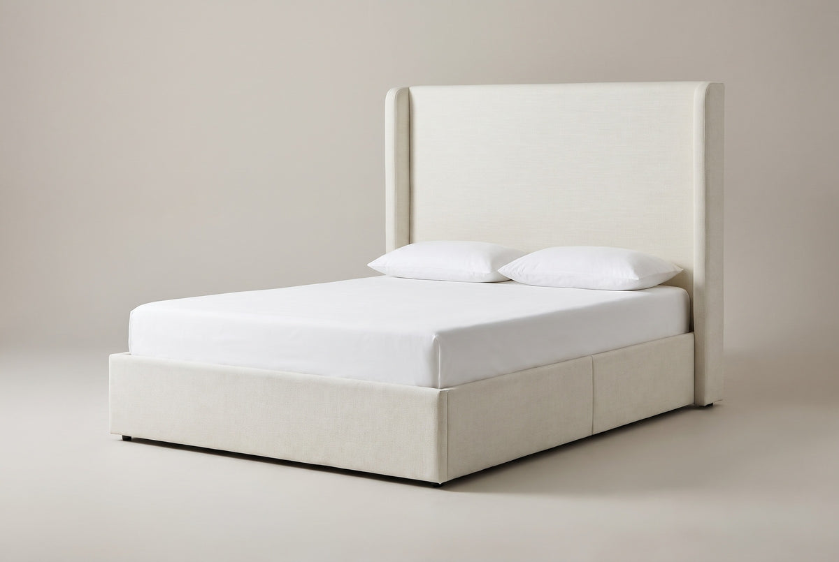 The Scanno ivory canvas wingback bed with a tall flat headboard, two slim wings, a deep base, a white mattress and pillows (not included), three-quarter view on a light studio backdrop