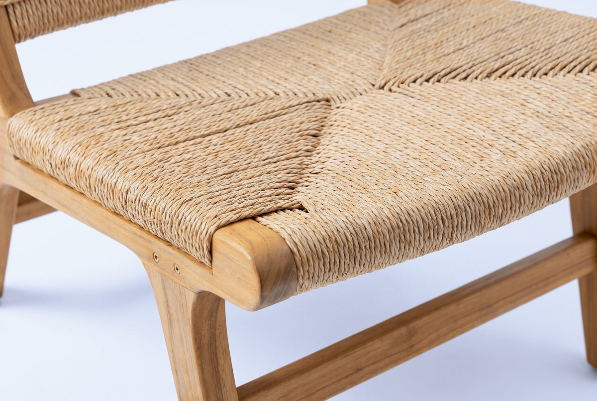 Close-up of a Scopello chair seat: the twisted PE wicker weave meeting at a V in the middle, the honey acacia front lip and a brass-coloured screw