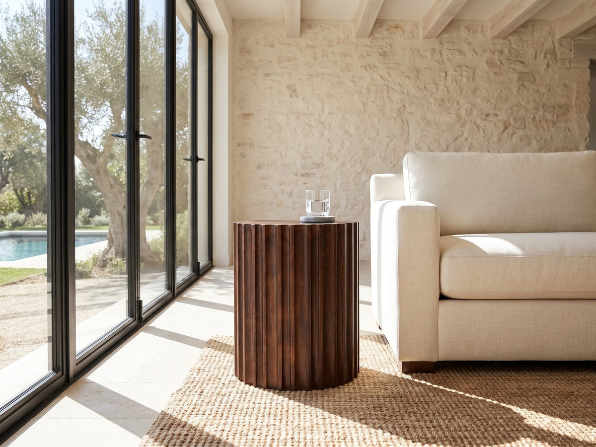 Senise Walnut Mango Fluted Drum Side Table beside a linen sofa in a poolside villa