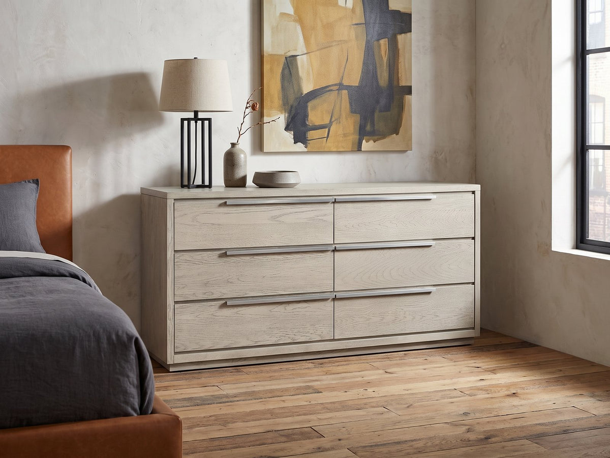 Sesto 63-Inch Gray Oak 6-Drawer Dresser against a plaster wall in an industrial loft bedroom