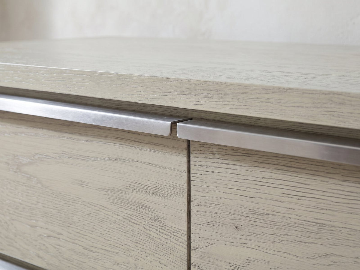 Close-up of the Sesto 63-Inch Gray Oak 6-Drawer Dresser: the brushed steel edge pulls meeting at the centre seam