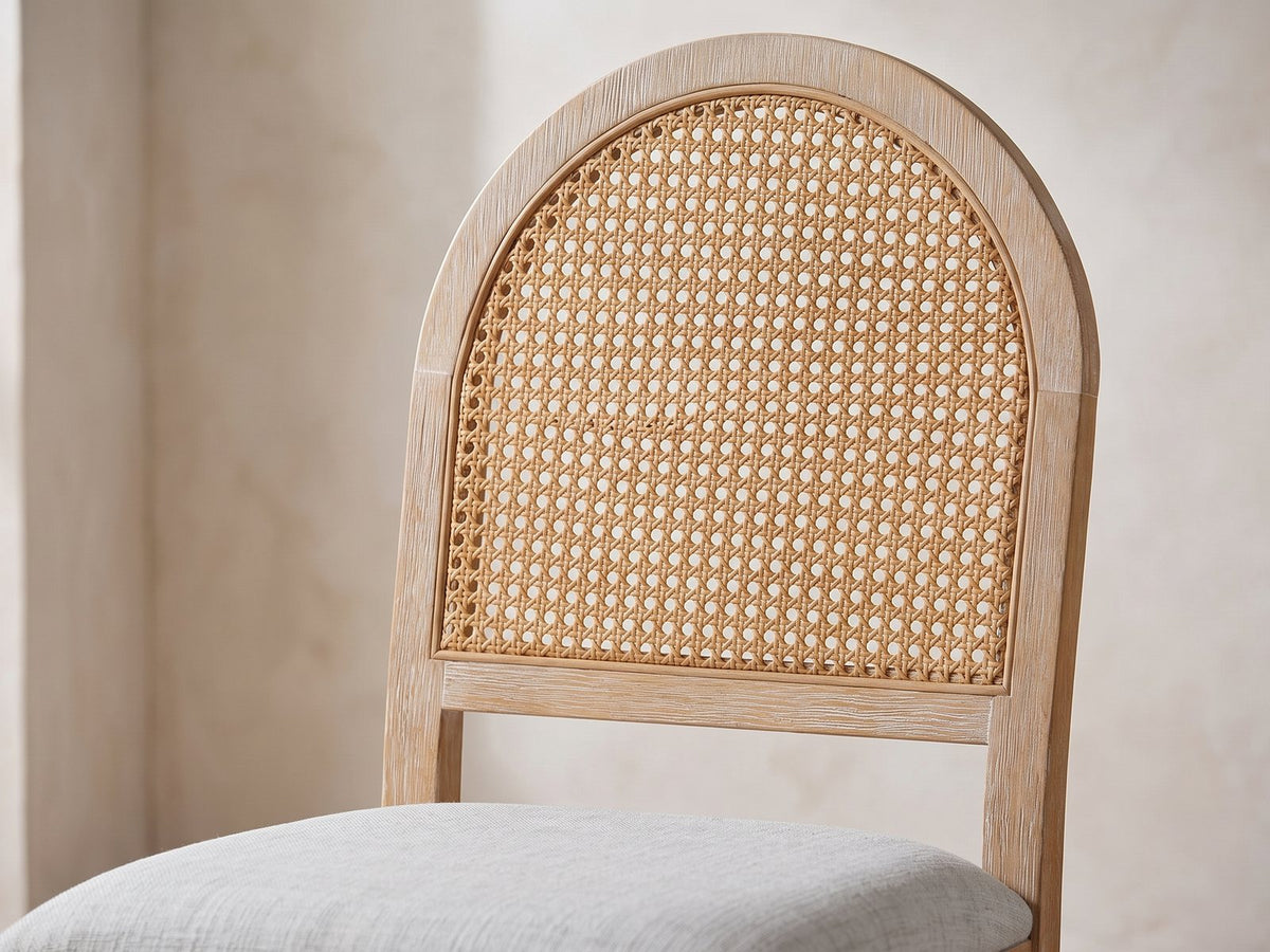 Close-up of the Siderno 42-Inch Extending Round Dining Set with 4 Chairs: the round-arched back with its woven cane-look panel and the light grey fabric seat