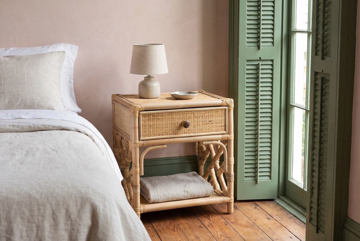Sinnai rattan nightstand against a blush pink plaster wall in a New Orleans bedroom with green shutters