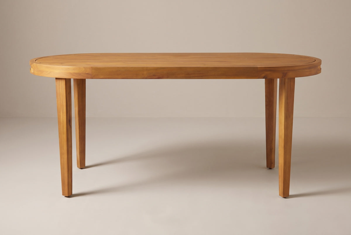 The Siracusa oval dining table on its own, seen from the long side: slatted top, curved rim and four tapered acacia legs