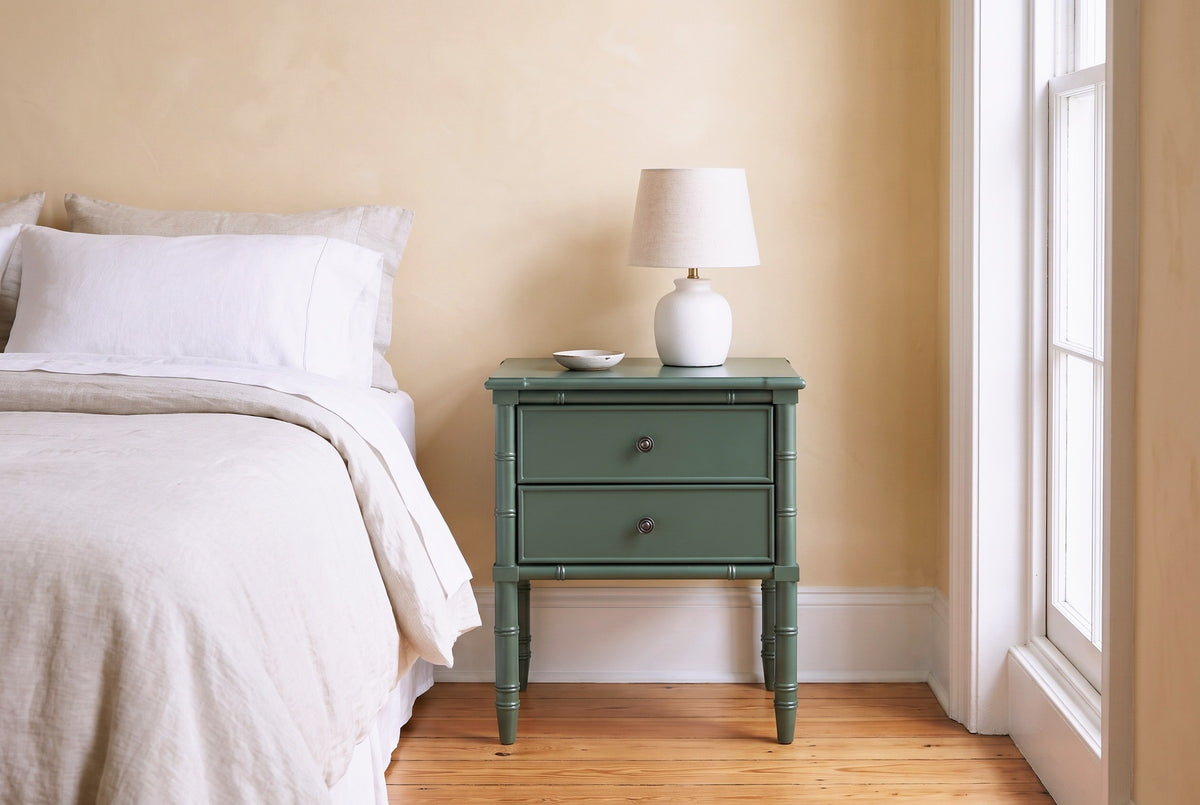 Sorgono green faux-bamboo nightstand against a butter-yellow plaster wall in a Charleston bedroom with heart-pine floors