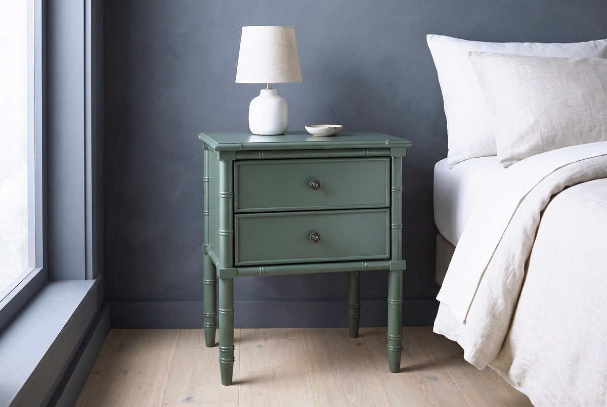Sorgono green faux-bamboo nightstand with a ceramic lamp against a slate grey limewashed wall in a Seattle bedroom