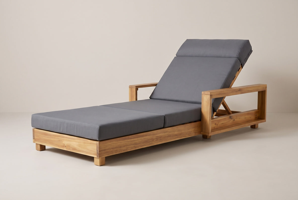 The Sortino acacia chaise lounge with a dark grey cushion, three-quarter view from the foot end on a light studio backdrop