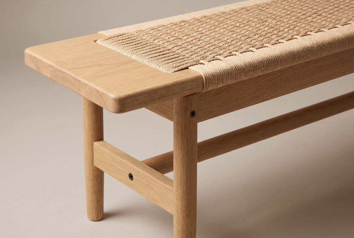 One end of the Sperlonga bench: the flat oak end block with a rounded corner, the paper cord seat beside it, the oak side rail below, a round tapered leg and the flat stretcher with the long round rail