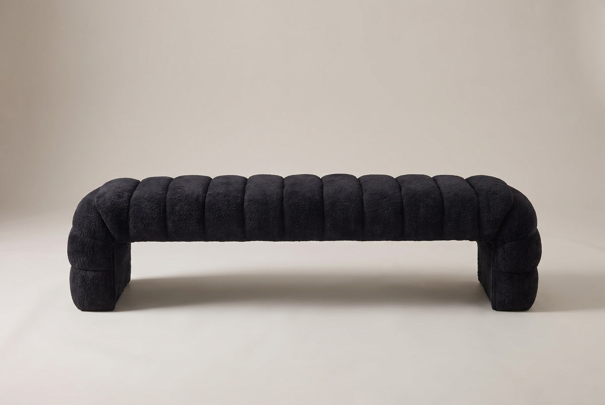 The Spoleto bench in black chenille, front view on a light studio backdrop: nine channels, a rolled end channel at each end and two solid end panels