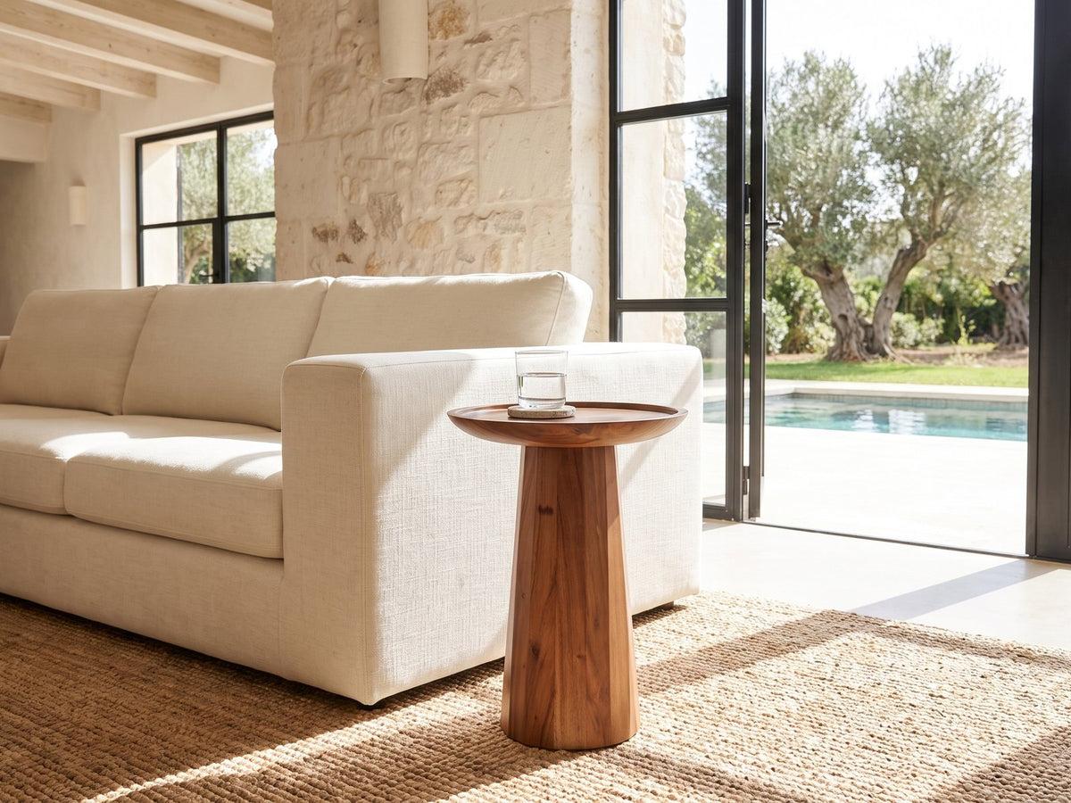 Sternatia Cognac Acacia Pedestal Side Table beside a linen sofa in a poolside villa