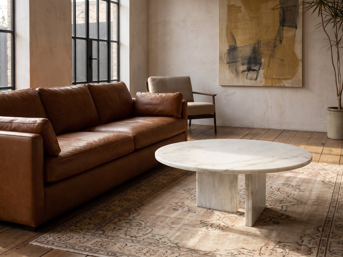 Stintino White Marble Coffee Table on a vintage rug in front of a leather sofa in an industrial loft