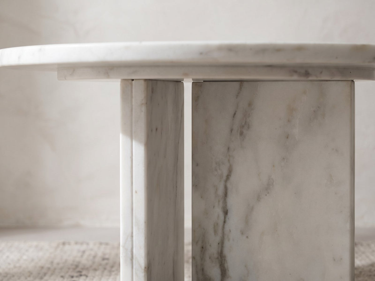 Close-up of the Stintino White Marble Round Side Table: the two white marble slabs of the base set in an open T under the top