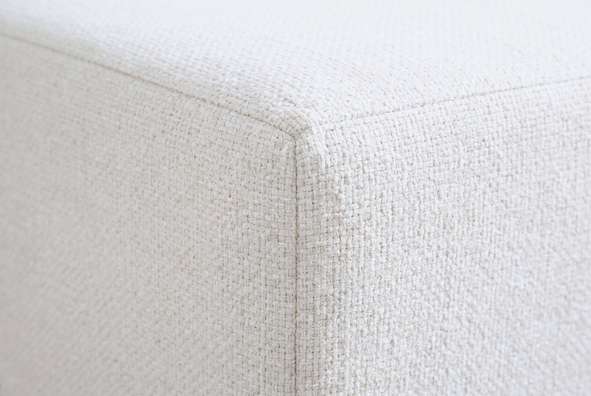 Close-up of the ivory textured canvas on the Sulmona bed where a flat rail face meets its corner along a plain seam