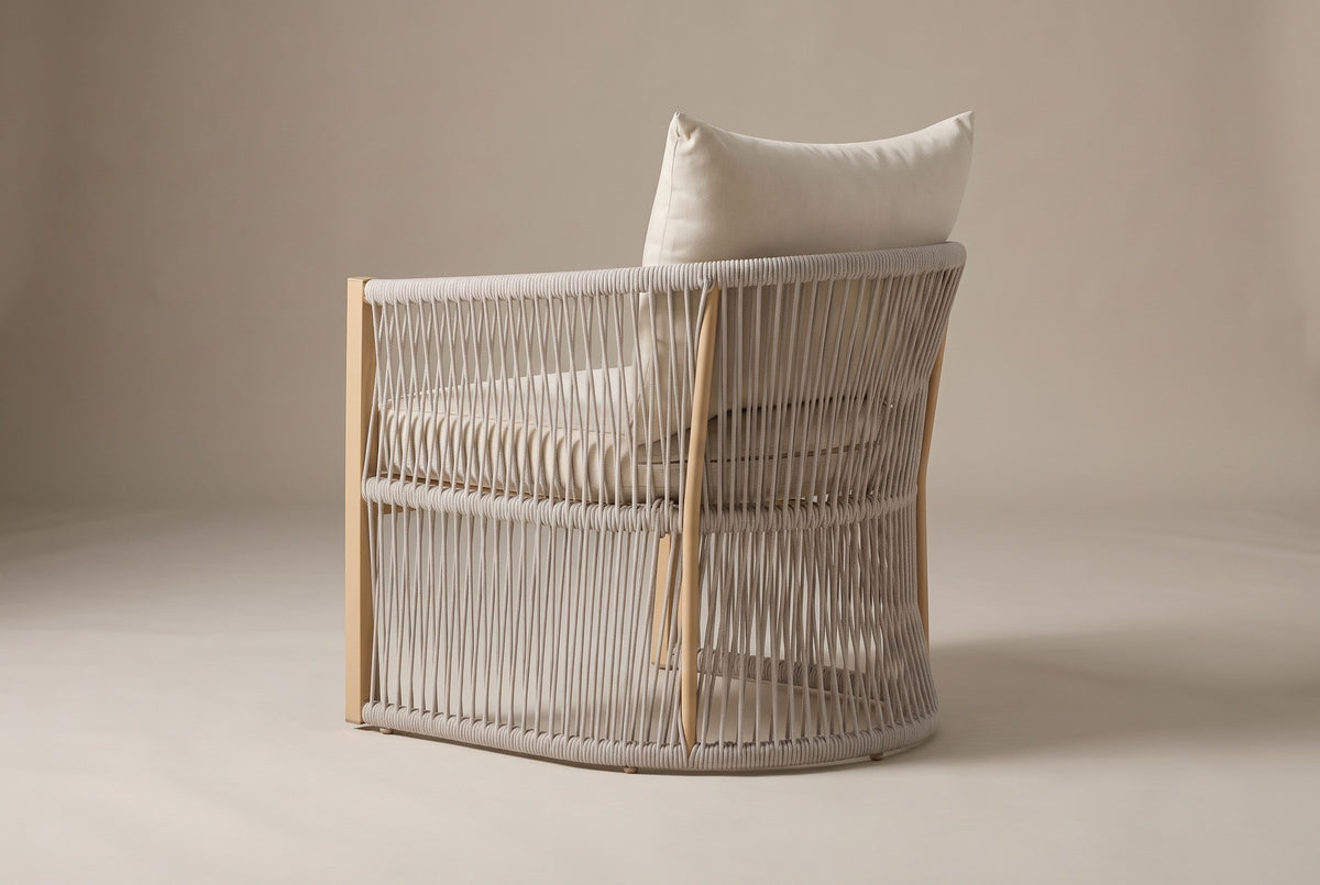 The Sutera chair from behind: the curved rope shell with its top, middle and floor rails and the sand-colored uprights