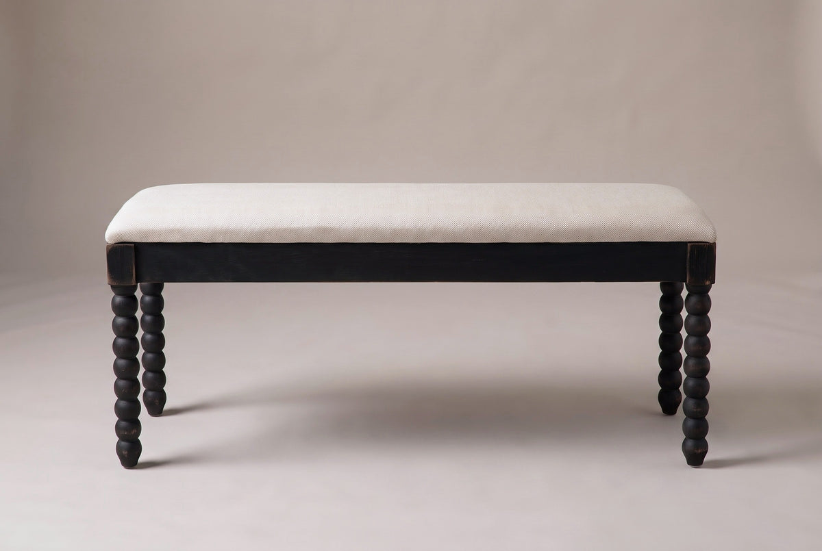 The Sutri bench in matte black with an oatmeal linen seat, straight front view on a light studio backdrop