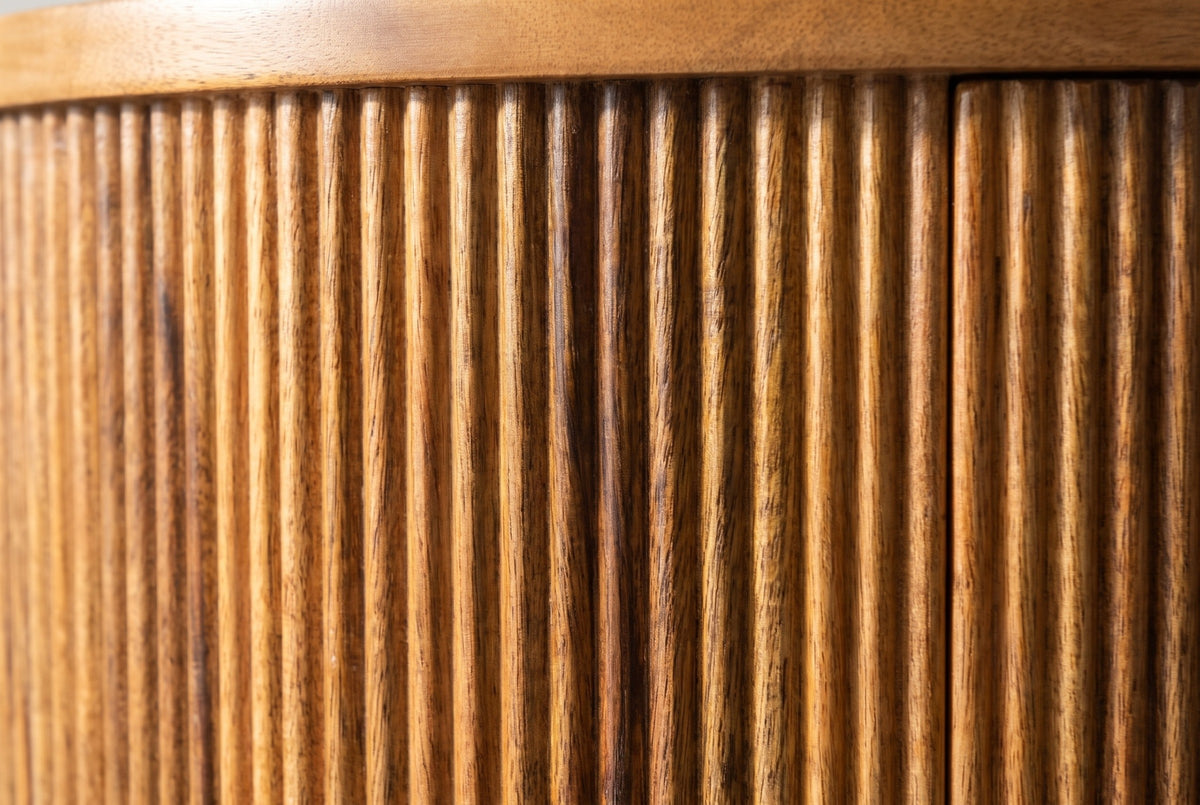 Close-up of the fine vertical reeds in golden brown mango wood on the Thiesi nightstand, under the smooth edge of the top