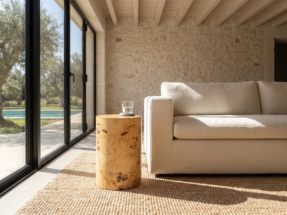 Tiriolo Natural Burl Pillar Side Table beside a linen sofa in a poolside villa