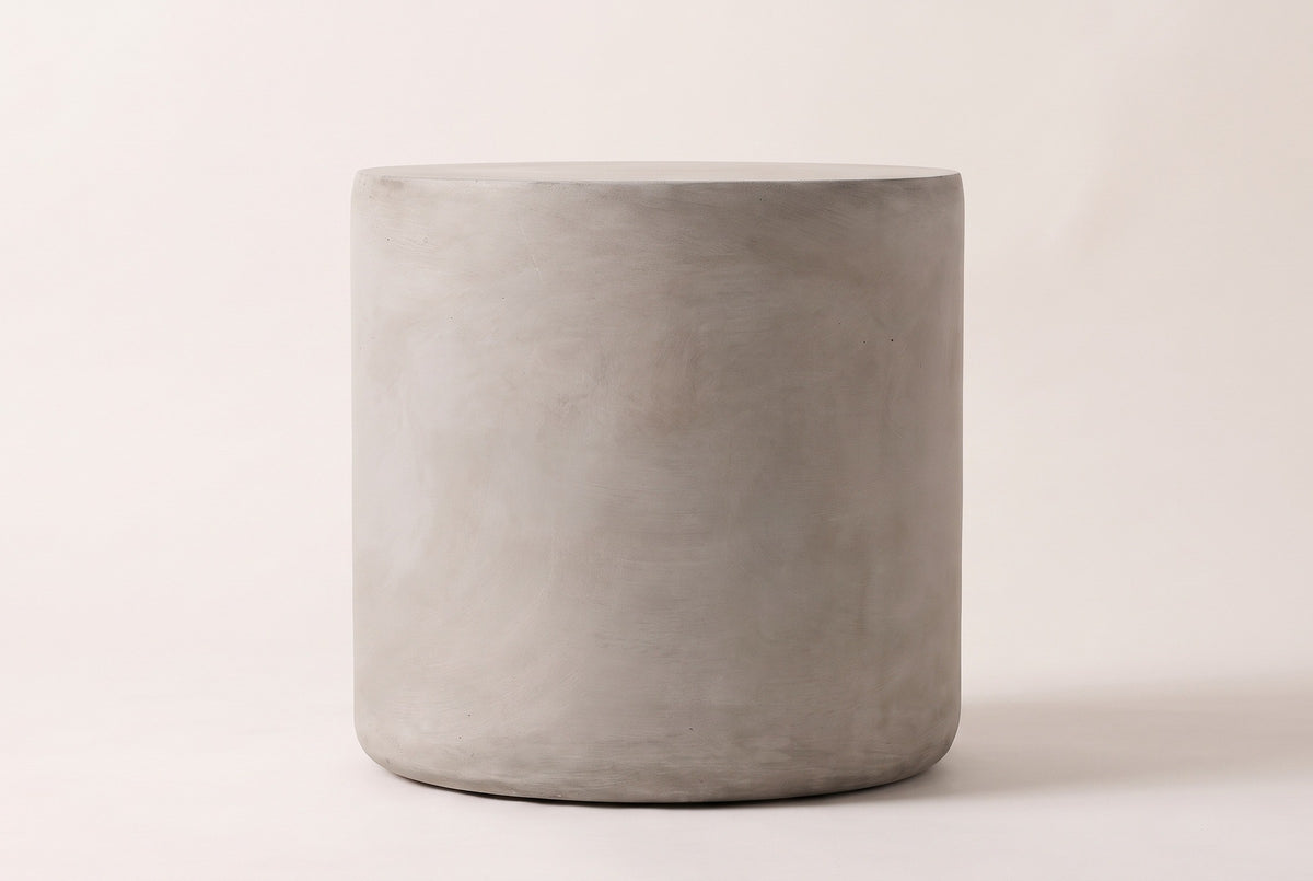 The Trabia side table seen straight from the side: a light grey concrete cylinder with straight sides and a softly rounded foot