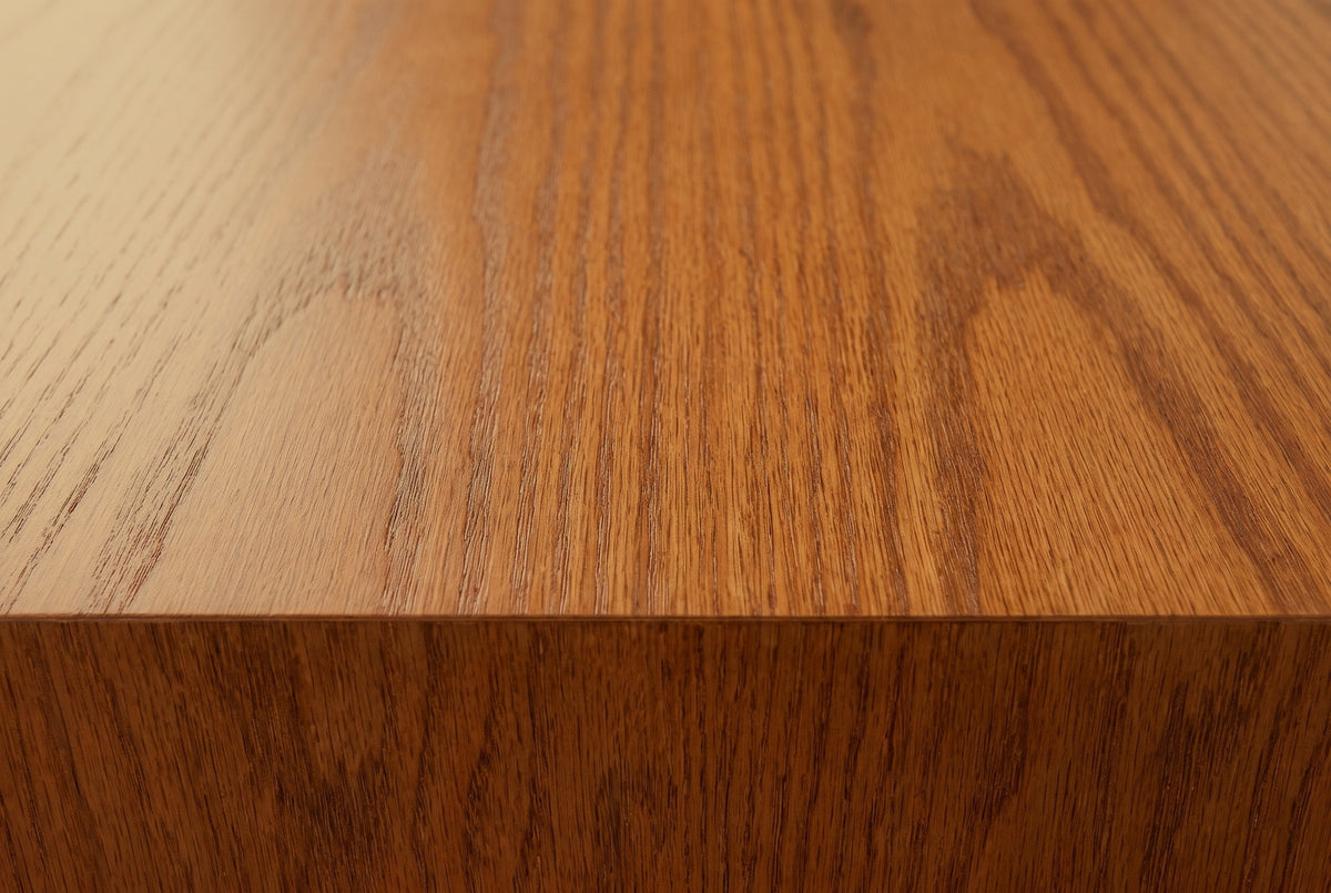 Close-up of the honey oak veneer on the Trani cabinet: open grain and cathedral arches running to a square edge