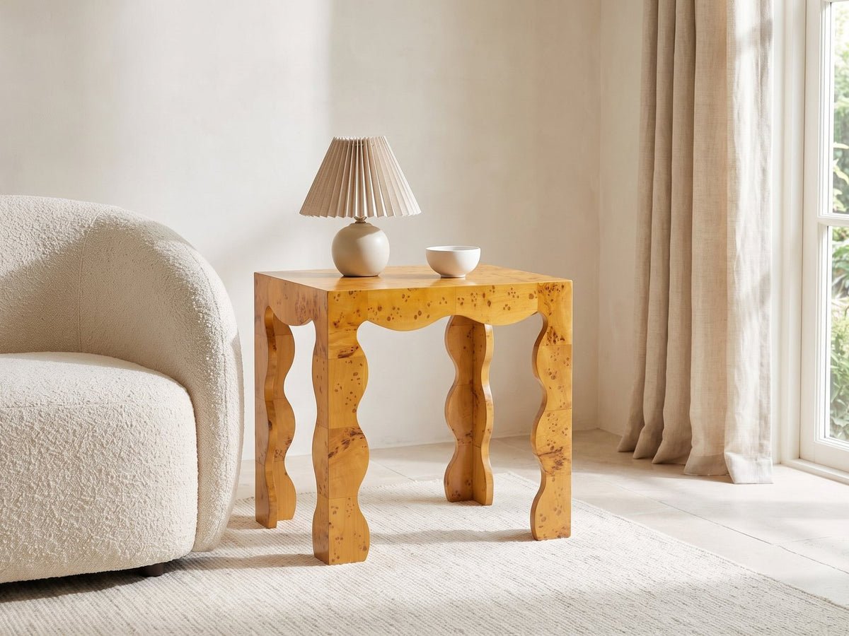Tricarico Burl Veneer Scalloped Side Table with a lamp and a ceramic bowl beside a cream boucle armchair in a bright plaster room