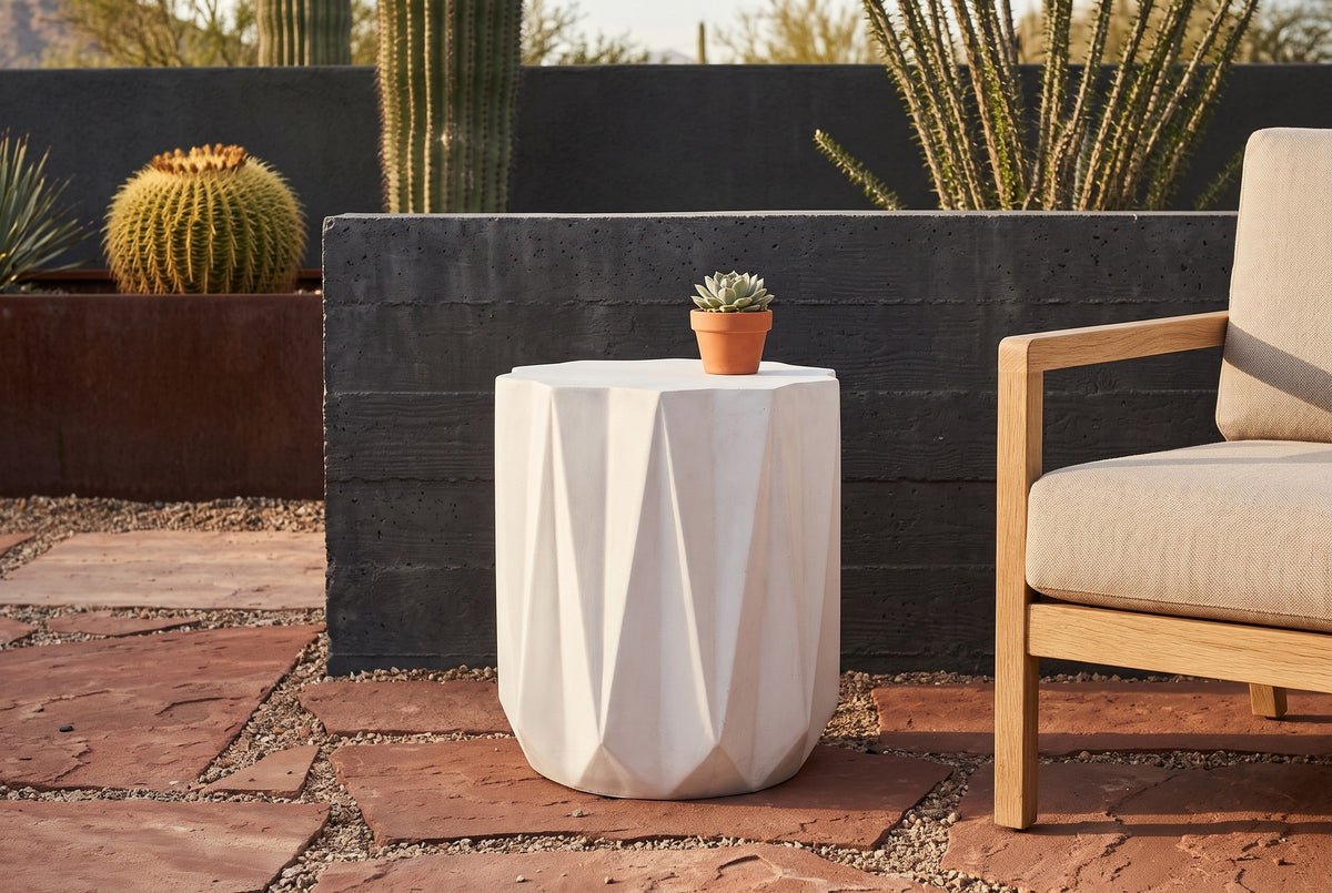Troina concrete side table on rust-red flagstone in a Tucson desert patio with a charcoal board-formed concrete wall and cactus, beside an oak armchair (chair and plant not included)