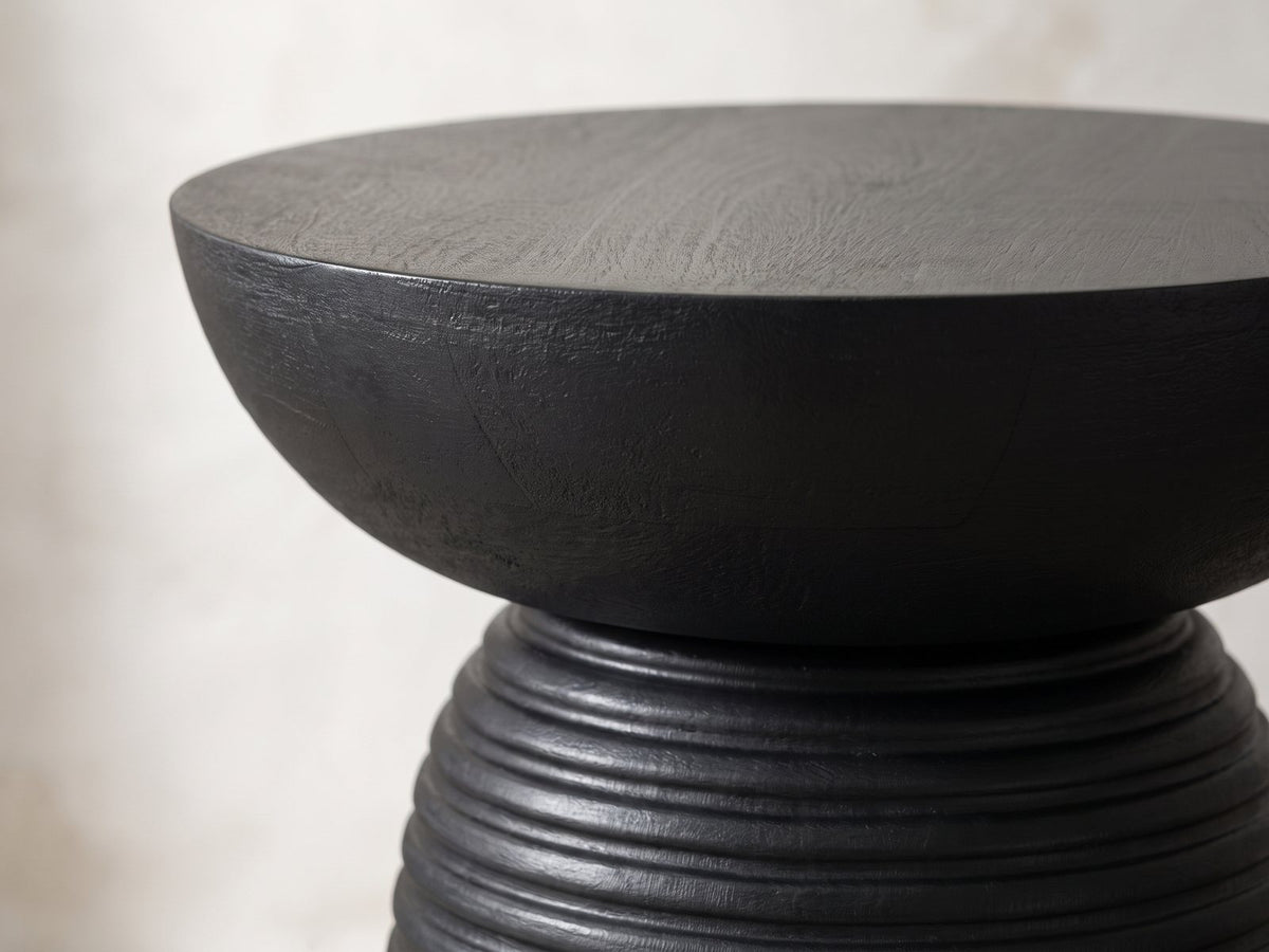 Close-up of the Tursi Black Mango Ribbed Pedestal Side Table: the smooth bowl-shaped top above the ribbed base