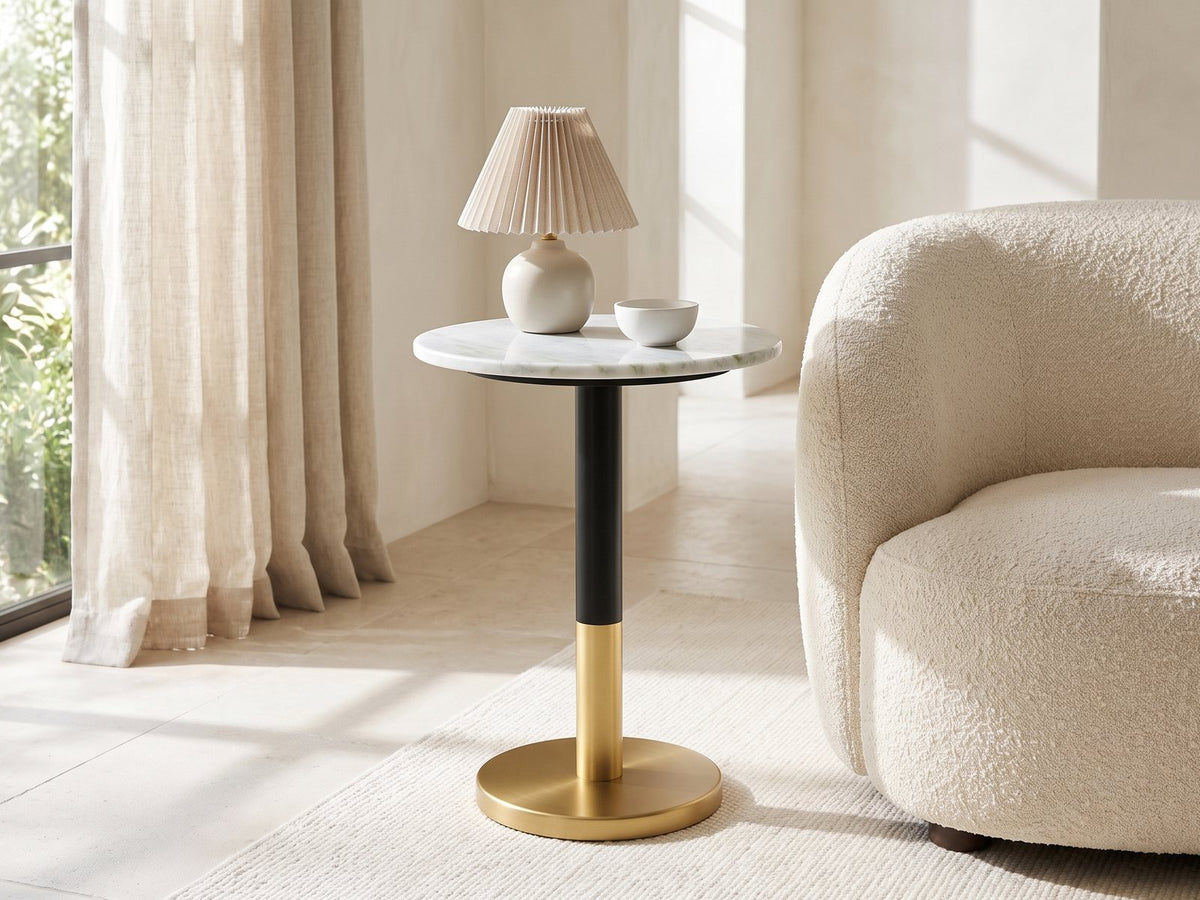 Ugento White Marble Pedestal Side Table with a lamp and a ceramic bowl beside a cream boucle armchair in a bright plaster room