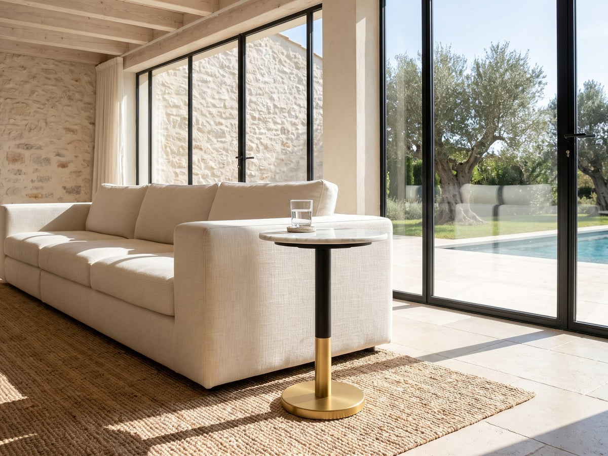 Ugento White Marble Pedestal Side Table beside a linen sofa in a poolside villa