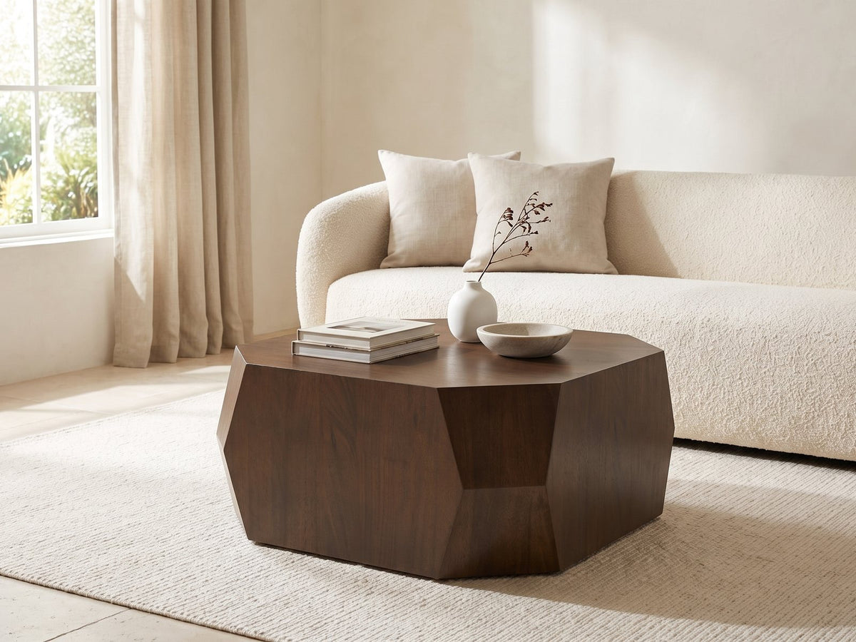 Urbino Acacia Veneer Faceted Coffee Table styled with books, a vase and a stone bowl in front of a cream sofa in a bright plaster room