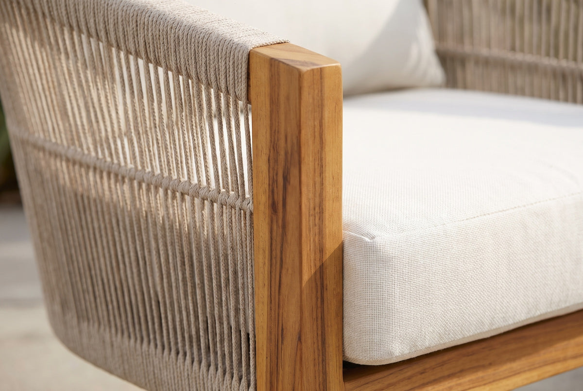 Close-up of the Ustica chair: handwoven beige rope with a horizontal band, a flat solid acacia post in teak finish and the edge of the seat cushion