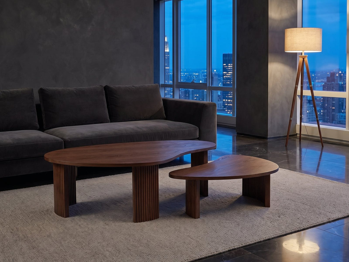 Valenza 50-Inch Freeform Walnut-Stained Veneer Nesting Coffee Tables, Set of 2 on a wool rug in front of a velvet sofa in a city penthouse at blue hour