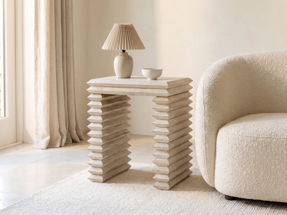Varallo Reclaimed Pine Side Table with a lamp and a ceramic bowl beside a cream boucle armchair in a bright plaster room