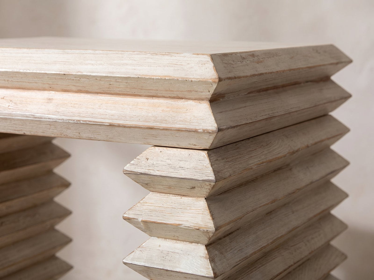 Close-up of the Varallo Reclaimed Pine Side Table: the stepped top edge over the bevelled pine slats of a leg