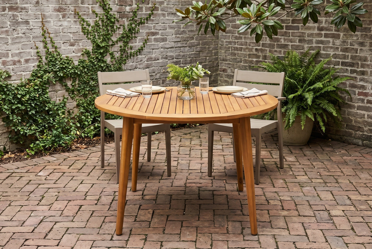 Vittoria round acacia dining table in a Savannah courtyard with an old grey brick wall, creeping fig and herringbone brick paving (chairs and tableware not included)