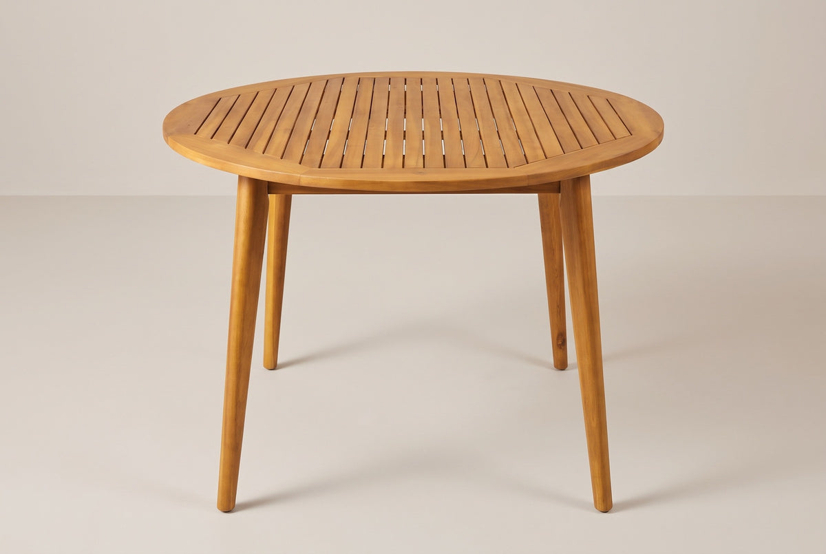 The Vittoria round acacia dining table in teak finish on a light studio backdrop (sold without chairs)