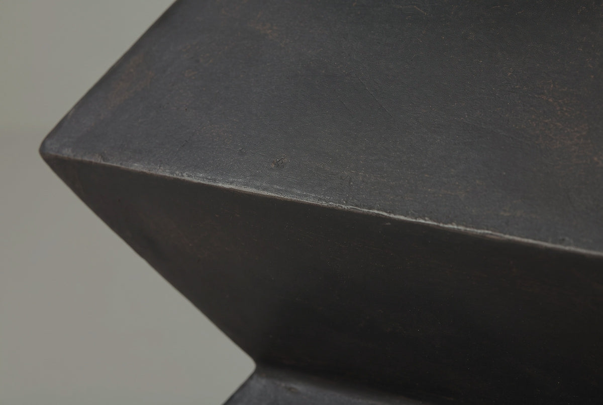 Close-up of the charcoal bronze lightweight concrete on the Zafferana side table, with faint warm brushed marks along an edge