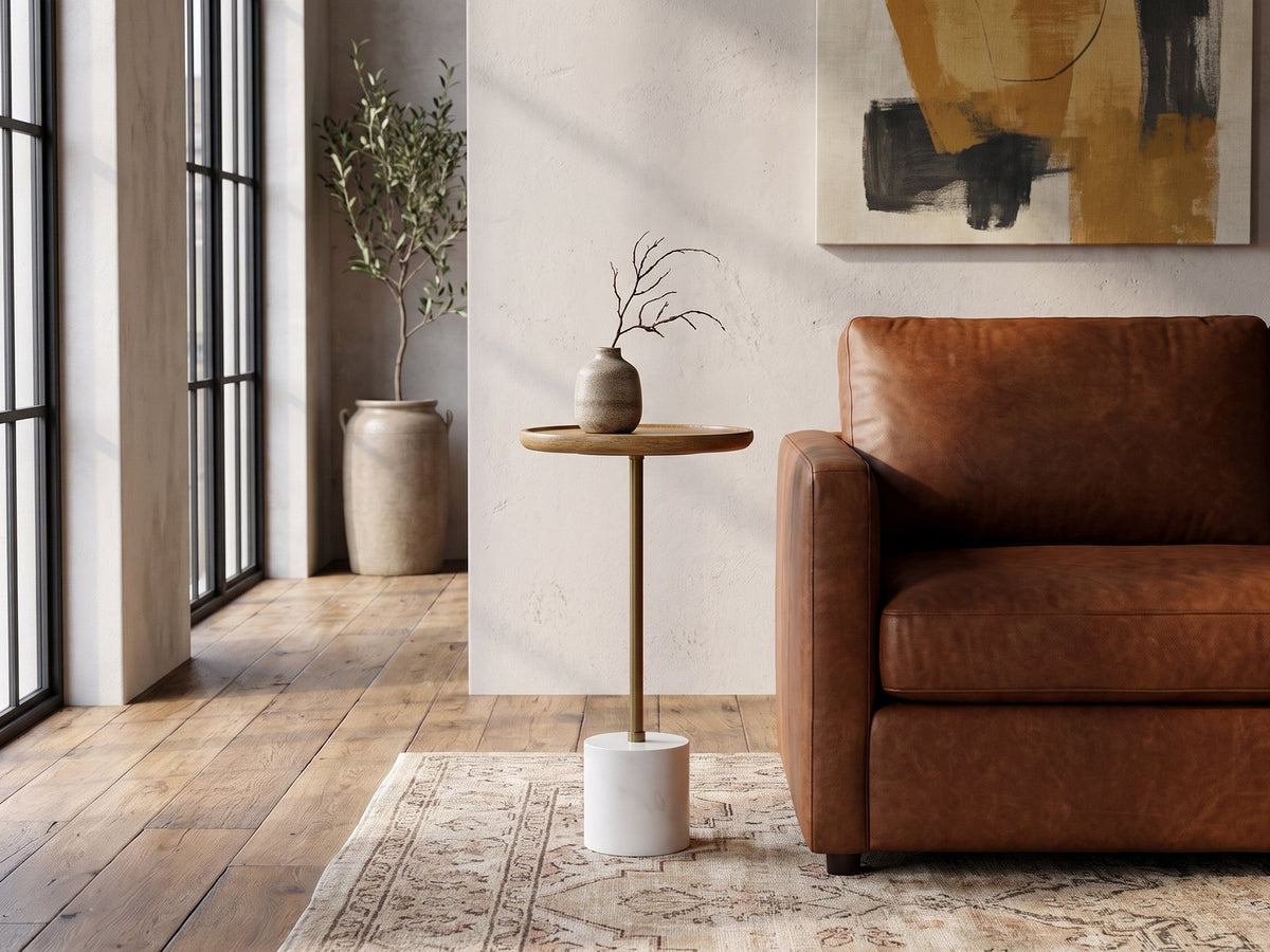 Zollino Mango and Marble Pedestal Side Table beside a cognac leather armchair in an industrial loft