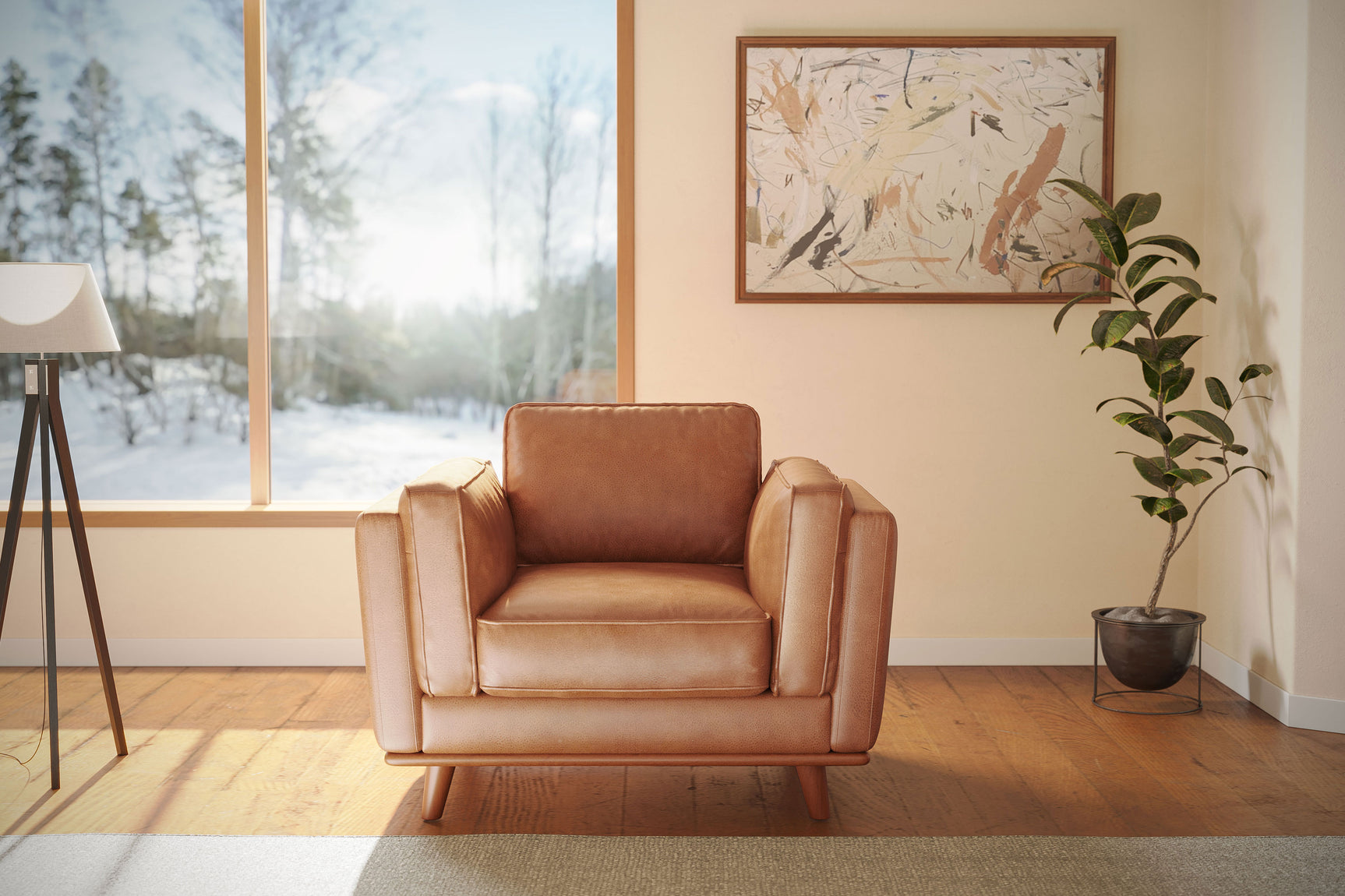 A Valencia Artisan Leather Accent Chair in Cognac color, placed on a rug in a room with wooden floors. It's beside a floor lamp, near a large window showing a snowy outdoor view. An abstract painting hangs on the wall above it, and a potted plant is nearby, highlighting the chair's stylish and cozy appeal.
