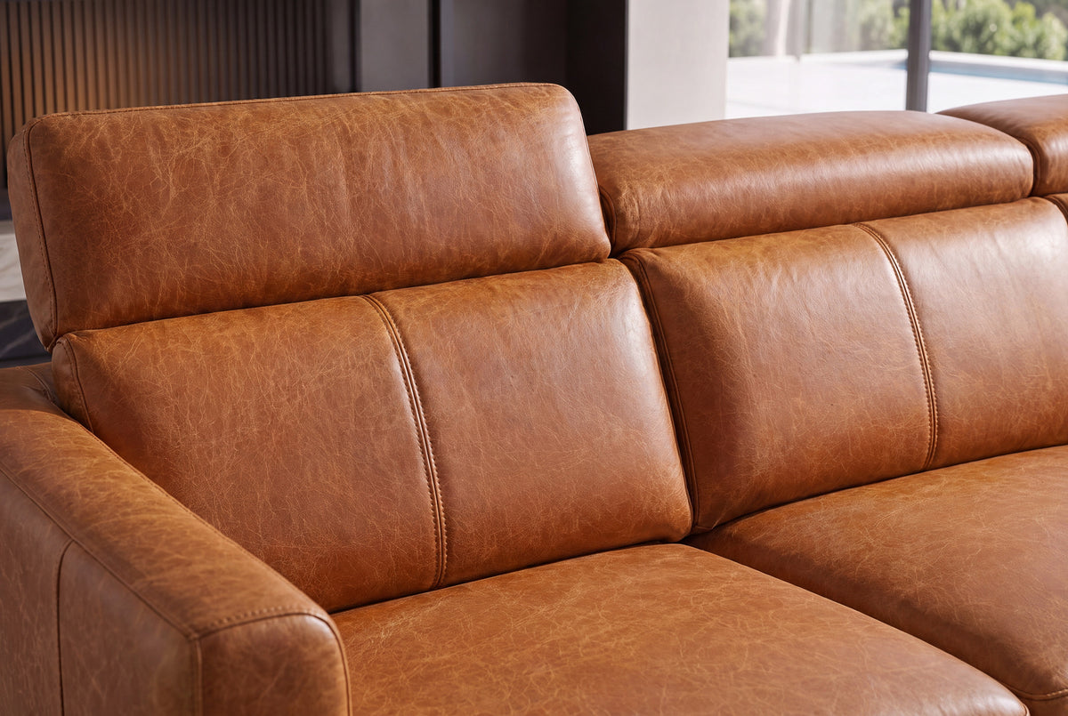 Close-up of Andria cognac leather seat cushions, adjustable headrests, and padded armrest