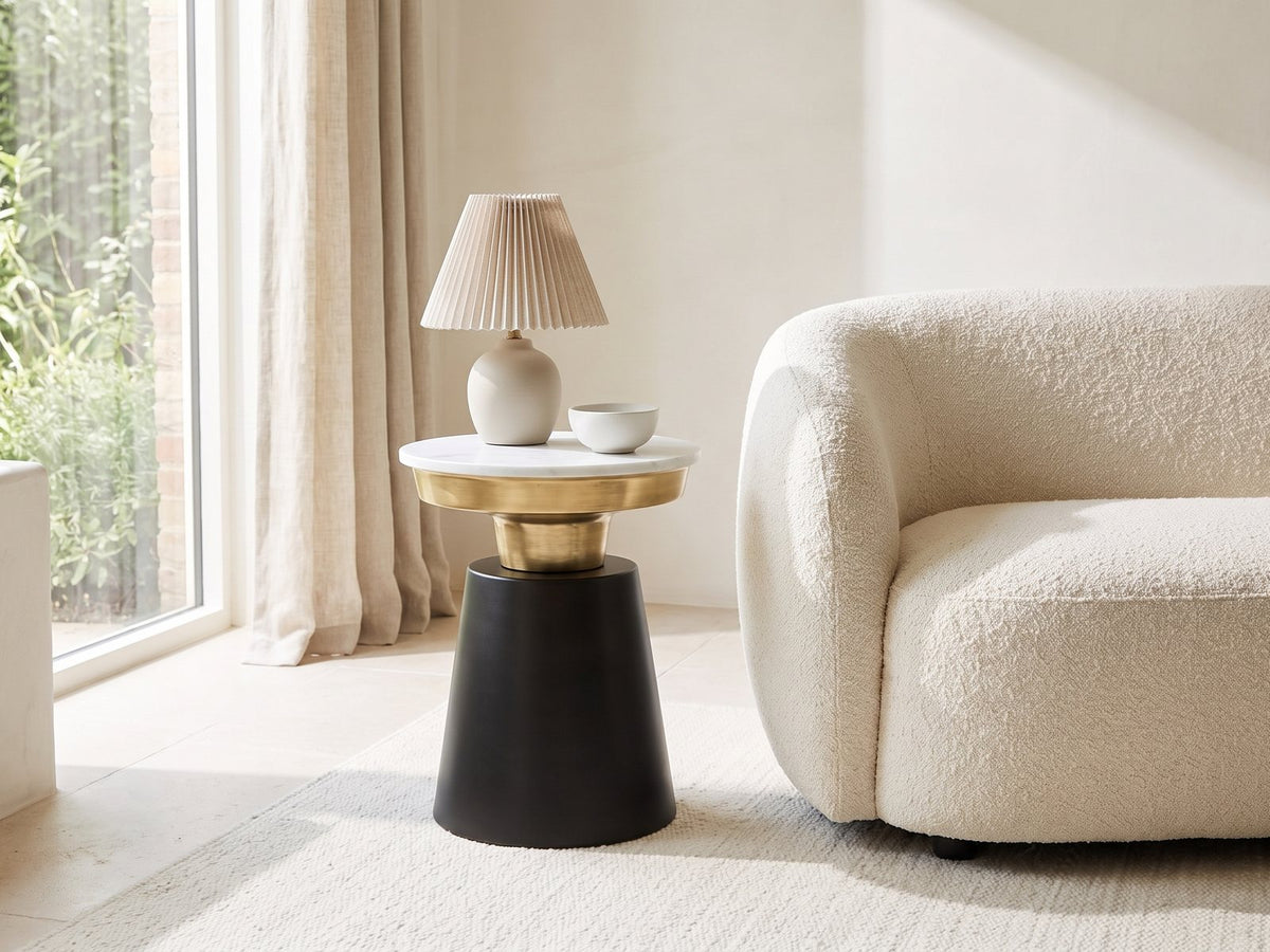 Acerenza White Marble Pedestal Side Table with a lamp and a ceramic bowl beside a cream boucle armchair in a bright plaster room
