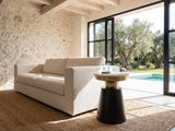 Acerenza White Marble Pedestal Side Table beside a linen sofa in a poolside villa