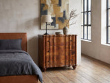 Adria 34-Inch Chestnut Solid Mango 3-Drawer Chest against a plaster wall in an industrial loft bedroom