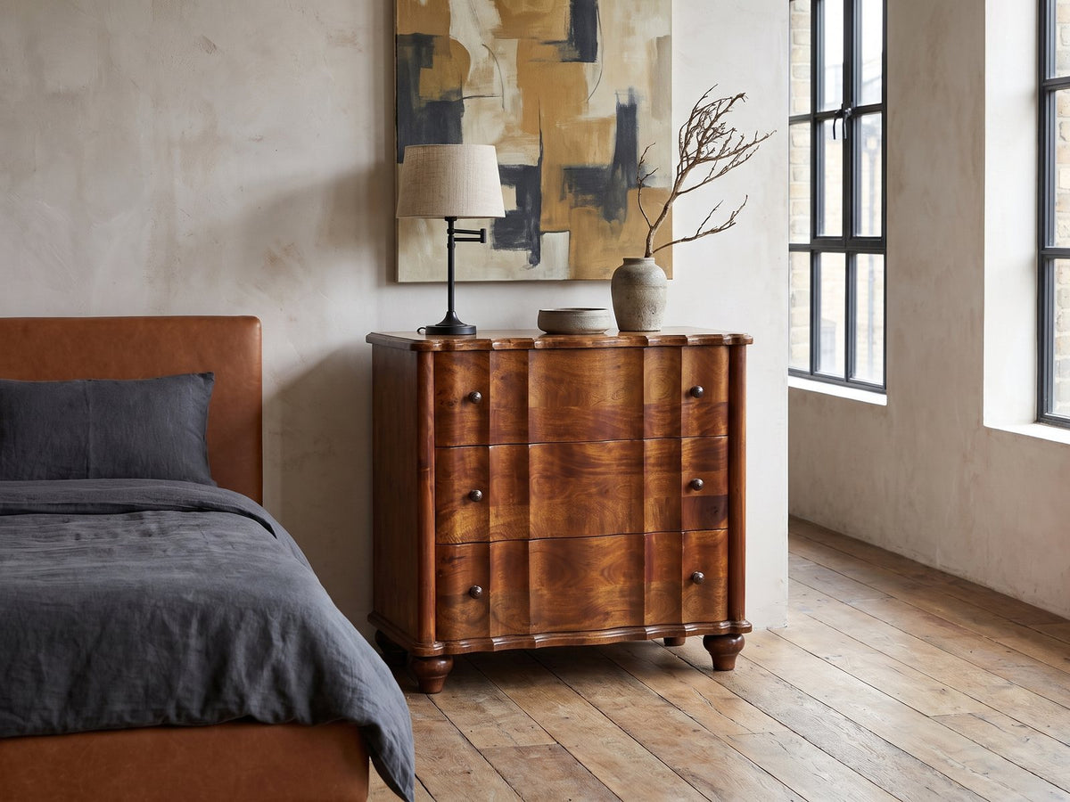 Adria 34-Inch Chestnut Solid Mango 3-Drawer Chest against a plaster wall in an industrial loft bedroom